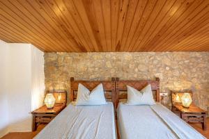 two beds in a room with wooden ceilings at Eco Masias Cal Ferran in El Bruc +24 photos