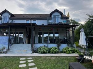 a house with a balcony and a bunch of bananas at Cozy Lake House in Cinciş