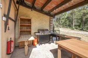 an outdoor kitchen with a grill and a table at Eco Masias Cal Ferran in El Bruc