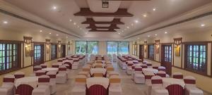 a banquet hall with white chairs and tables and windows at Avana Resort in Mettuppālaiyam +107 photos