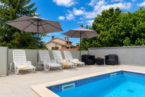 a group of chairs and umbrellas next to a swimming pool at Magnolia by Briskva in Vinež