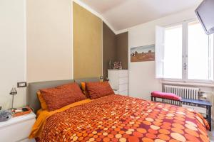 a bedroom with a bed with an orange comforter and a window at De' Fusari, Bologna by Short Holidays in Bologna