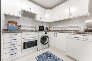 a kitchen with white cabinets and a washer and dryer at Doña Sofía in Fuengirola