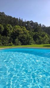 a pool of blue water with trees in the background at Ferreirinha Valley in Vieira do Minho