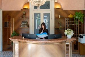 a woman sitting at a counter with two laptops at Hotel Maderno by Double Hospitality in Toscolano Maderno +86 photos