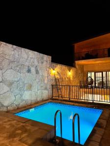 a pool at night with a rock wall at Sargsyans house in Dilijan