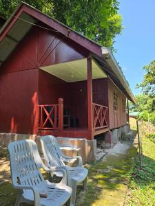 two white chairs sitting outside of a red building at D view hill hotel in Kuala Tahan