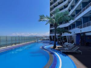 a swimming pool with a palm tree and a building at SL Hotel Gangneung in Gangneung