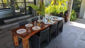 a wooden table with chairs and plates on it at Life is One in Uluwatu