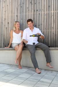 a man and a woman sitting on a bench with drinks at Ferienwohnung Königshofer in Neusiedl am See