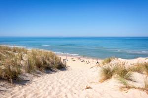 a beach with people on the sand and the ocean at Charmant studio in Saint-Aubin-de-Médoc