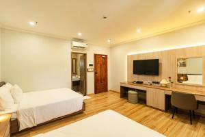 a bedroom with a bed and a desk with a television at Khach san Binh Ha in Quy Nhon