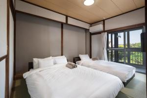 two white beds in a room with a window at オーシャンステイみうら in Miura
