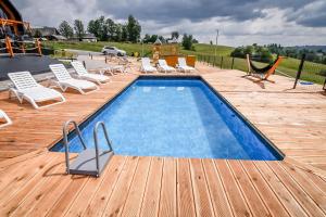 a swimming pool on a wooden deck with lounge chairs at Maruszyna Resort & SPA in Zakopane