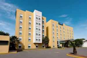 a large building with palm trees in a parking lot at City Express by Marriott Saltillo Sur in Saltillo