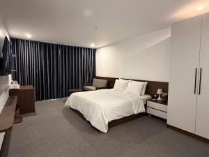 a bedroom with a large white bed and a chair at Minh Hai Hotel Lao Bao in Lao Bao