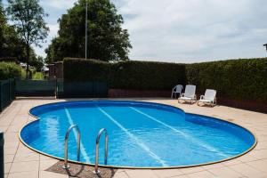 a large blue swimming pool with two chairs in a yard at A View for Two in Tarchamps