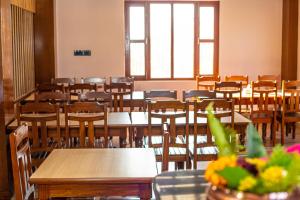 an empty classroom with tables and chairs and windows at Himalaya Forest Resort in Deorāli
