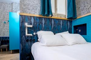 a bedroom with blue walls and a bed with white pillows at Hôtel Crayon Rouge - Louvre Palais Royal in Paris