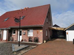 a brick house with a red roof and a driveway at Ferienhaus Moorspatz, 95143 in Rhauderfehn