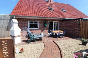 a brick house with a red roof and a patio at Ferienhaus Moorspatz, 95143 in Rhauderfehn
