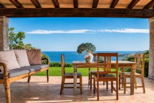 a patio with a table and chairs and the ocean at Big Pevero Sea View House 8 Three Bedrooms in Porto Cervo