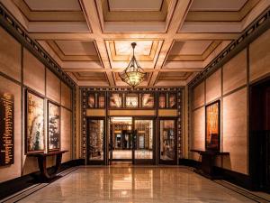 an empty lobby with a chandelier in a building at Fairmont Peace Hotel on the Bund in Shanghai