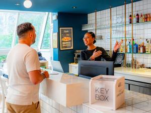 a man and a woman standing at a cash register at Mercure Paris Montparnasse Pasteur in Paris