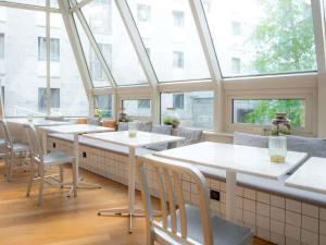 a restaurant with white tables and chairs and windows at Mercure Paris Montparnasse Pasteur in Paris