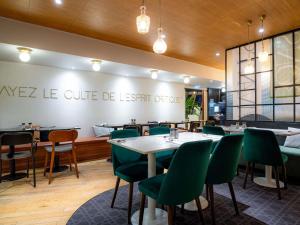 a restaurant with green chairs and tables in a room at Mercure Paris Montparnasse Pasteur in Paris