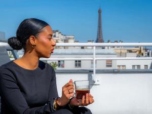 a woman sitting on a ledge holding a drink at Mercure Paris Montparnasse Pasteur in Paris