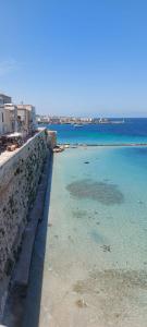 a beach with blue water and a stone wall at Appartamento Patty in Cannole
