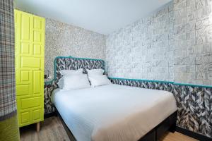 a bedroom with a bed and a yellow door at Hôtel Crayon Rouge - Louvre Palais Royal in Paris