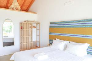 a bedroom with a white bed with a colorful headboard at Vale das Estrelas in São Teotónio