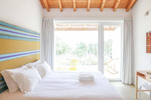 a bedroom with a bed and a large window at Vale das Estrelas in São Teotónio