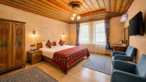 a bedroom with a bed and a tv and chairs at Cappadocia Elite Stone House in Göreme