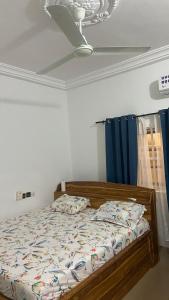 a bedroom with a bed and a ceiling fan at New ACROPOLE in Komé +4 photos