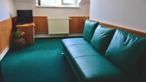 a green couch in a room with a television at Ubytovanie KRAS in Rožňava