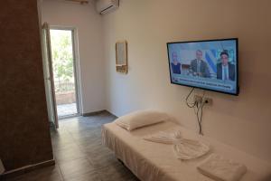 a room with a tv on a wall with a bed at Agora Apartments in Dhërmi