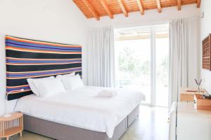 a white bedroom with a bed and a large window at Vale das Estrelas in São Teotónio