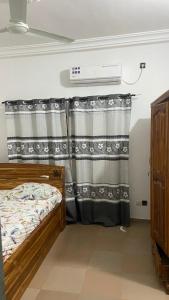 a bedroom with a bed and a curtain at New ACROPOLE in Komé