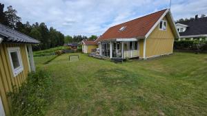 a yellow house with a yard with at Modern cosy house with forest views in Södertälje