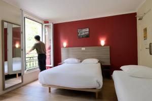 a man looking out the window of a bedroom at Hipotel Paris Gambetta République in Paris