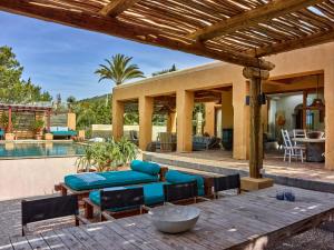 a patio with a blue couch and chairs next to a pool at Kasbah 2 in Sant Josep de sa Talaia
