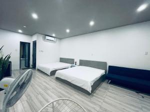 a bedroom with two beds and a blue couch at Coral Homestay Phan Rang in Kinh Dinh