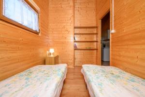 two beds in a room with wooden walls at Domki i pokoje nad morzem U Izy Jarosławiec in Jarosławiec