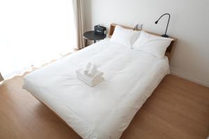 a white bed with two folded towels on it at Hotel Otsukahouse in Tokyo
