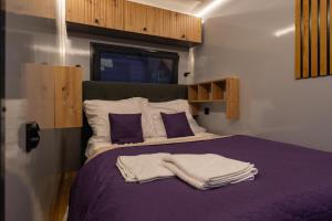 a bedroom with a purple bed with towels on it at Prague River Houseboats - Private Bay in Prague