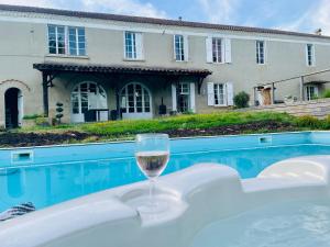 a glass of wine sitting on a table next to a swimming pool at Grand Gite Bidallon in Saint-Michel-Saint-Jaymes
