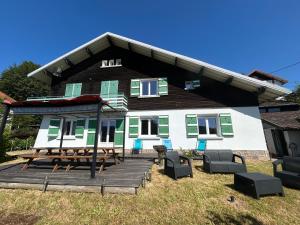 a house with a picnic table and chairs on a deck at Appartement RDC Chalet à 300m du lac de Gérardmer in Gérardmer